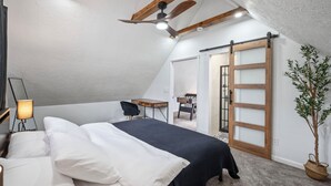 Un dormitorio con cama, escritorio, silla, lámpara, ventilador de techo y puerta corrediza.