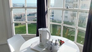 A room with a white table, two white chairs, a white kettle, two white mugs, and a tray with a spoon and a small container. - Central Wave Brighton  (Brighton)