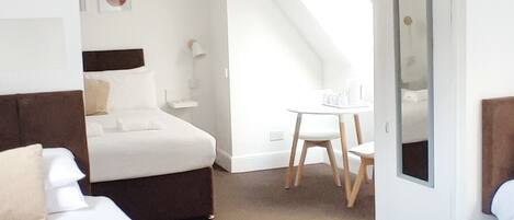 Ein Hotelzimmer mit Bett, Schreibtisch, Stuhl, Spiegel und einer Pendelleuchte.