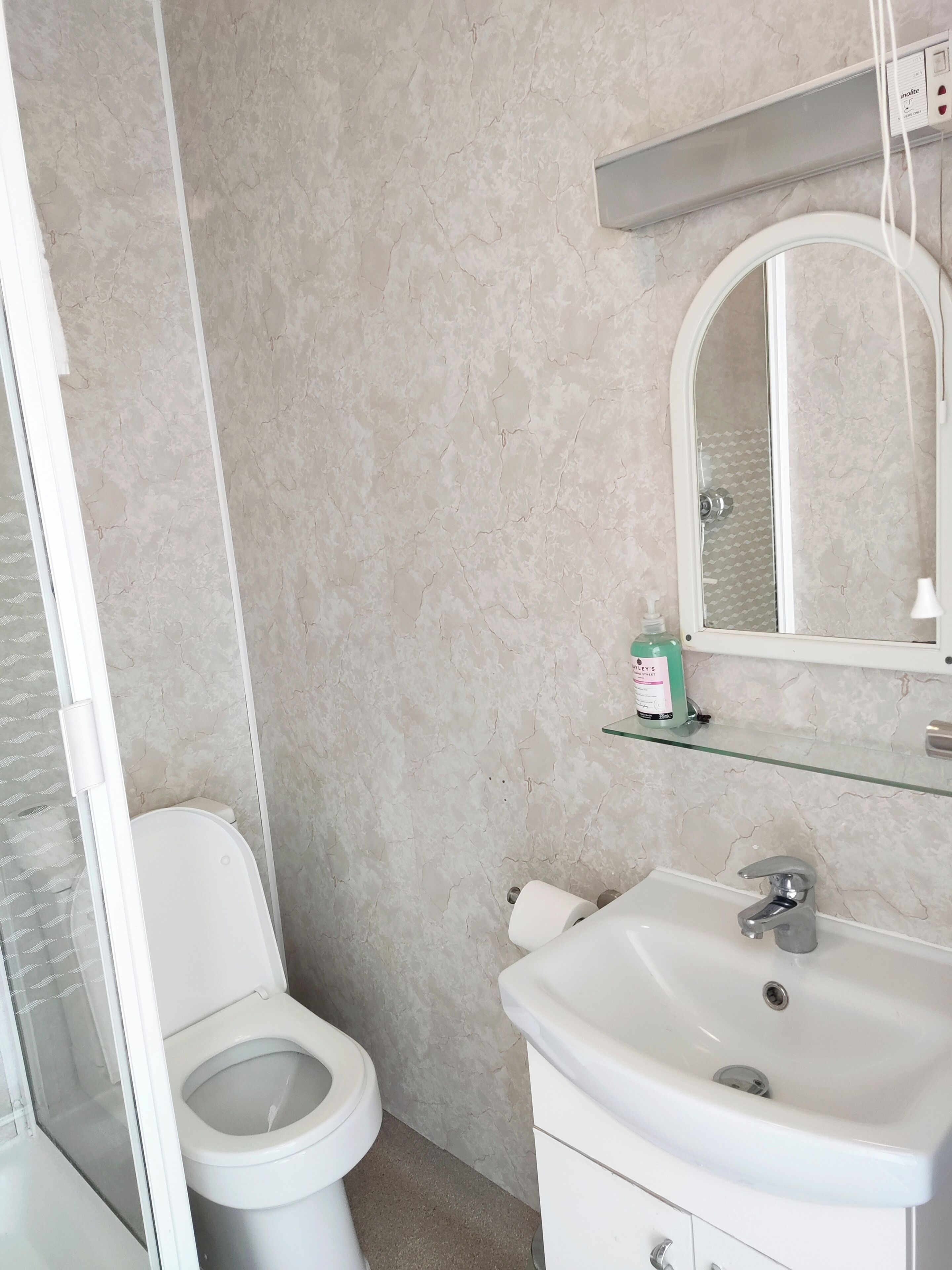 Ein Badezimmer mit Toilette, Waschbecken und Spiegel.