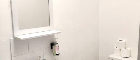 A bathroom with a white sink, mirror, and toilet.