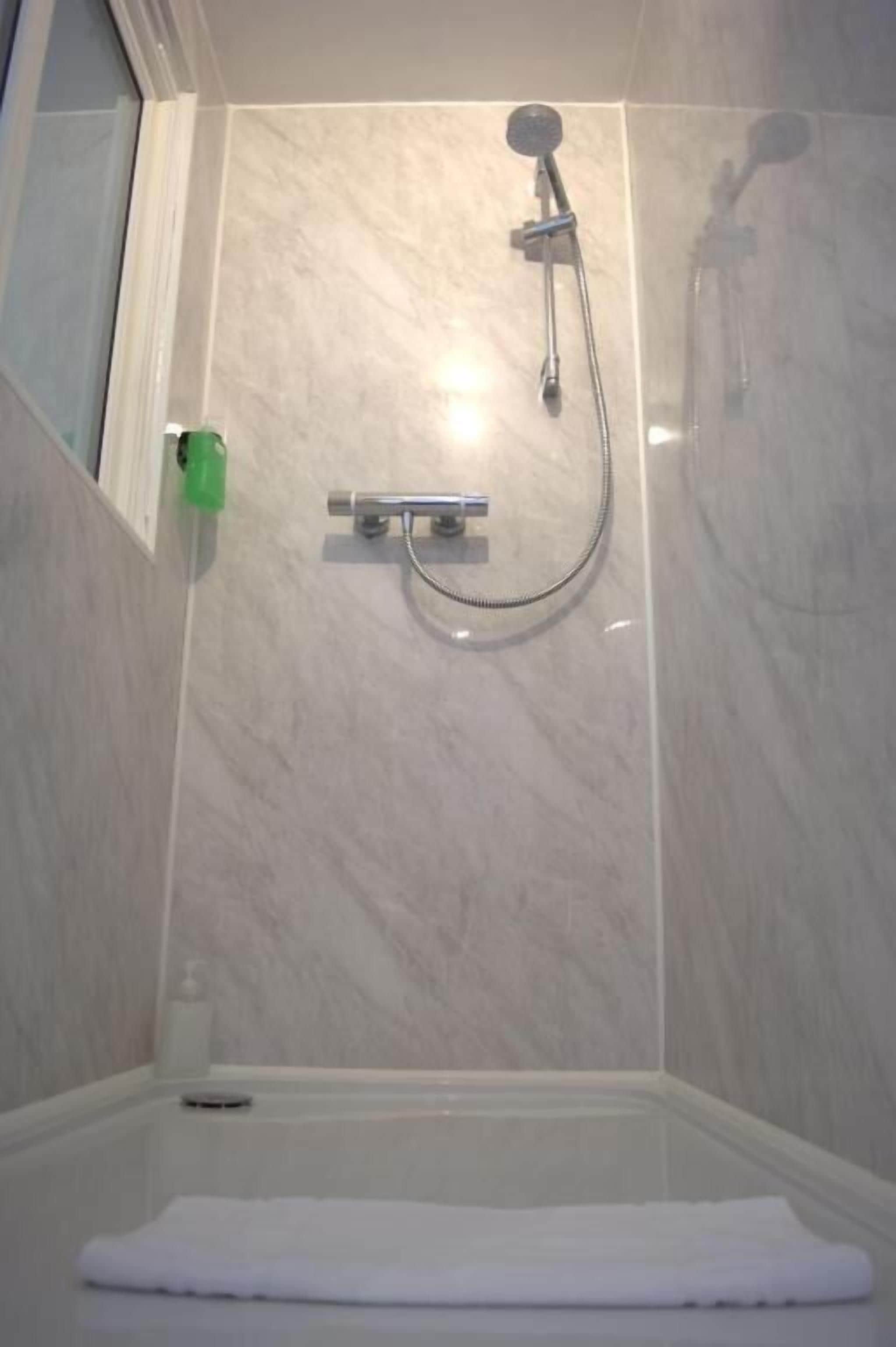 A bathroom with a shower, a toilet, and a towel on the floor.