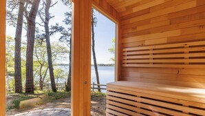 A wooden sauna with a view of a lake and trees. - Luxe Lakefront Retreat★Sauna★Media Rm★Kayaks-SUPs★Bikes★Steps to BikePath★Pet OK (Harwich)
