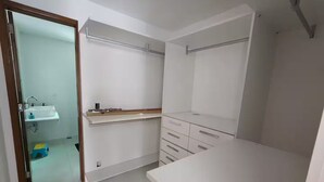 Um quarto com uma escrivaninha branca, uma cômoda branca e uma estante branca com um espelho.