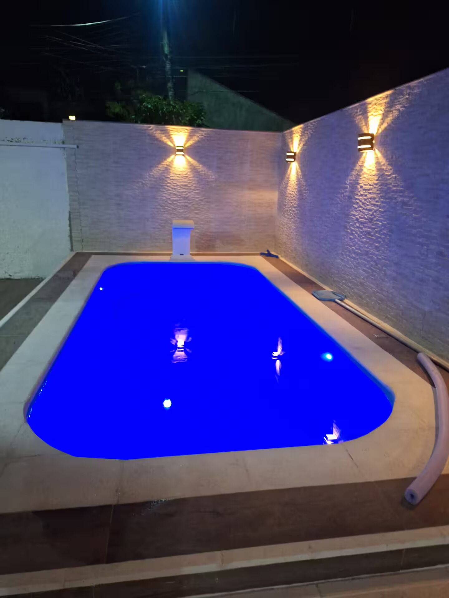 Une piscine à l’intérieur bleu, entourée de murs dans lesquels sont intégrés des luminaires.