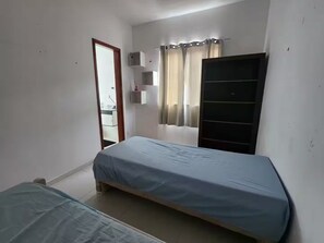 A small, single-bed room with a wooden bed frame, a wardrobe, a small shelf unit, and a window with curtains. - HOUSE, 4 SUITES, POOL, BARBECUE, COMFORT, SPACE AND TRANQUILITY (Serra Grande Niterói)