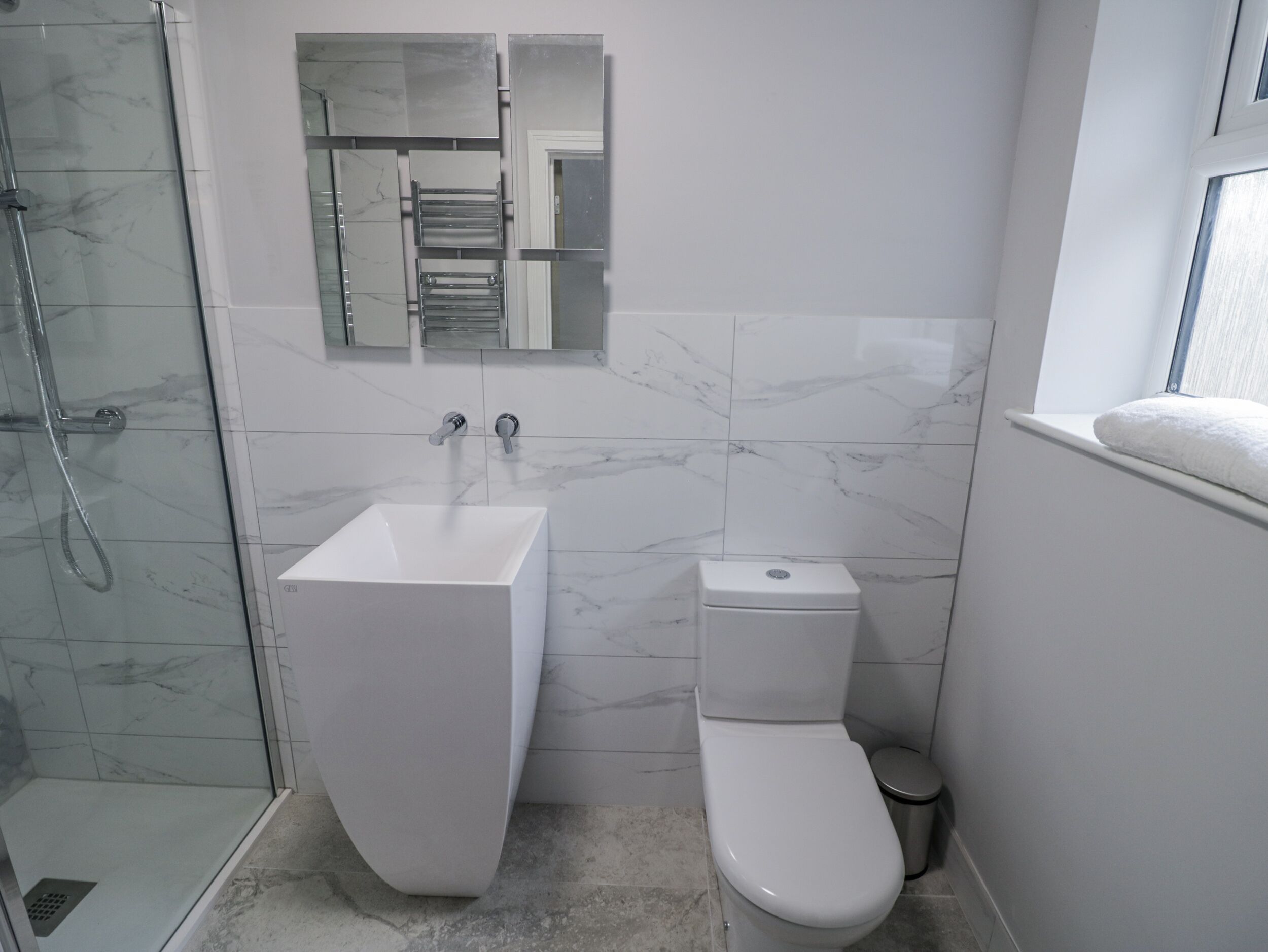 A bathroom with a glass-enclosed shower, a white sink, and a toilet.