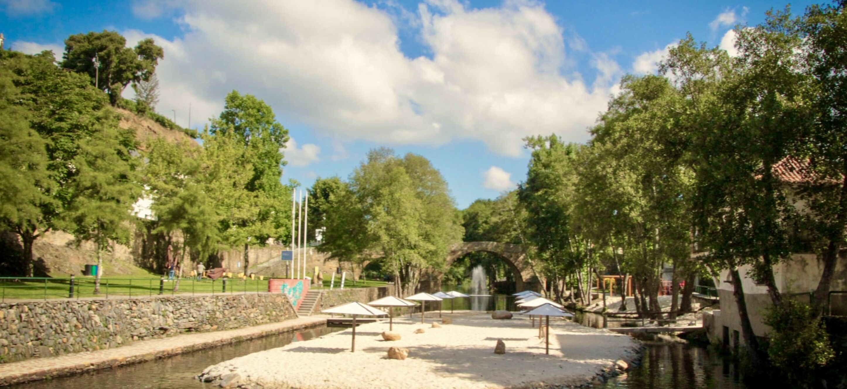 Een rustig park met een kanaal, stenen muren en bomen.