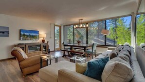 A modern living room with a sofa, a coffee table, a dining table with chairs, and a TV on a cabinet. - Bright and Cozy Lakeview Retreat #59 (Kings Beach)