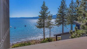 A coastal view with a clear sky, a rocky shoreline, and several tall pine trees. - Bright and Cozy Lakeview Retreat #59 (Kings Beach)