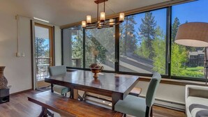A modern dining area with a large wooden table, multiple chairs, and a chandelier. - Bright and Cozy Lakeview Retreat #59 (Kings Beach)