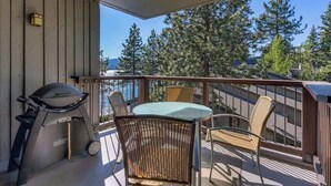 A balcony with wicker chairs, a table, and a Weber grill. - Bright and Cozy Lakeview Retreat #59 (Kings Beach)