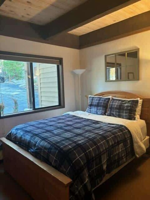 A bedroom with a bed, a window, a lamp, and a mirror.
