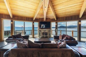 A cozy interior with a fireplace, large windows, and a view of the water.