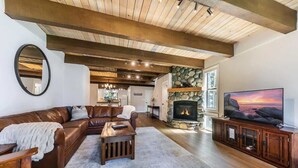 A spacious living room with a leather sofa, a coffee table, a fireplace, and a television.