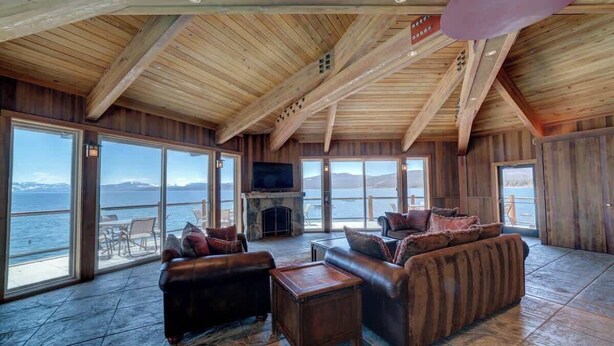 A spacious living room with a large TV, leather sofas, and a fireplace. - Brockway Springs Lake View Unit- #30 (Kings Beach)