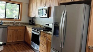 A modern kitchen with wooden cabinets, stainless steel appliances, and a window providing natural light. - Brockway Springs Lake View Unit- #30 (Kings Beach)