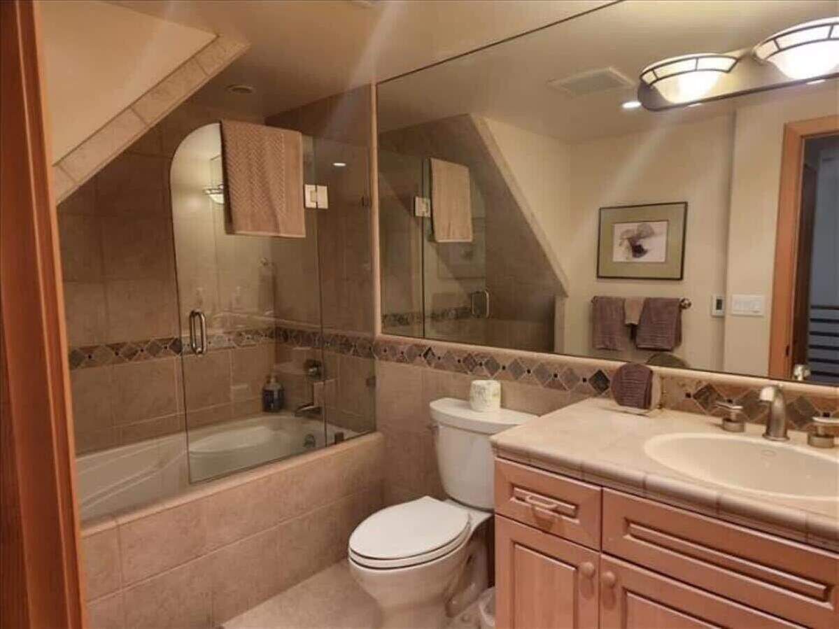 Un baño con ducha de mampara de vidrio, inodoro, lavabo y tocador.