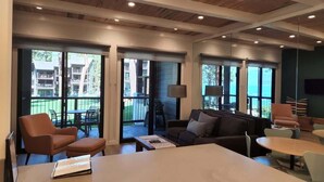 A modern living room with a large window, a sofa, a coffee table, and a TV. - Lakefront Condo in Kings Beach-#41 (Kings Beach)