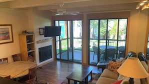 A spacious living room with a fireplace, a dining area, and a patio with outdoor furniture. - Lakefront Condo in Kings Beach-#33 (Kings Beach)