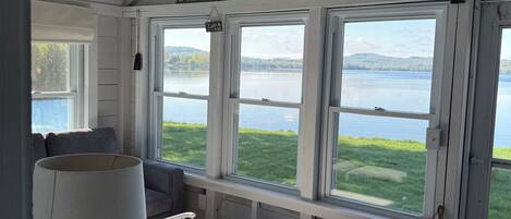 Una habitación acogedora con vistas a un lago, un banco de madera, una mesa con velas y un sillón colgante.
