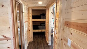 Un estrecho pasillo de madera con una cama litera al final.