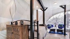 Une pièce aménagée comme une tente, avec un lit, une armoire en bois et des chaises bleues.
