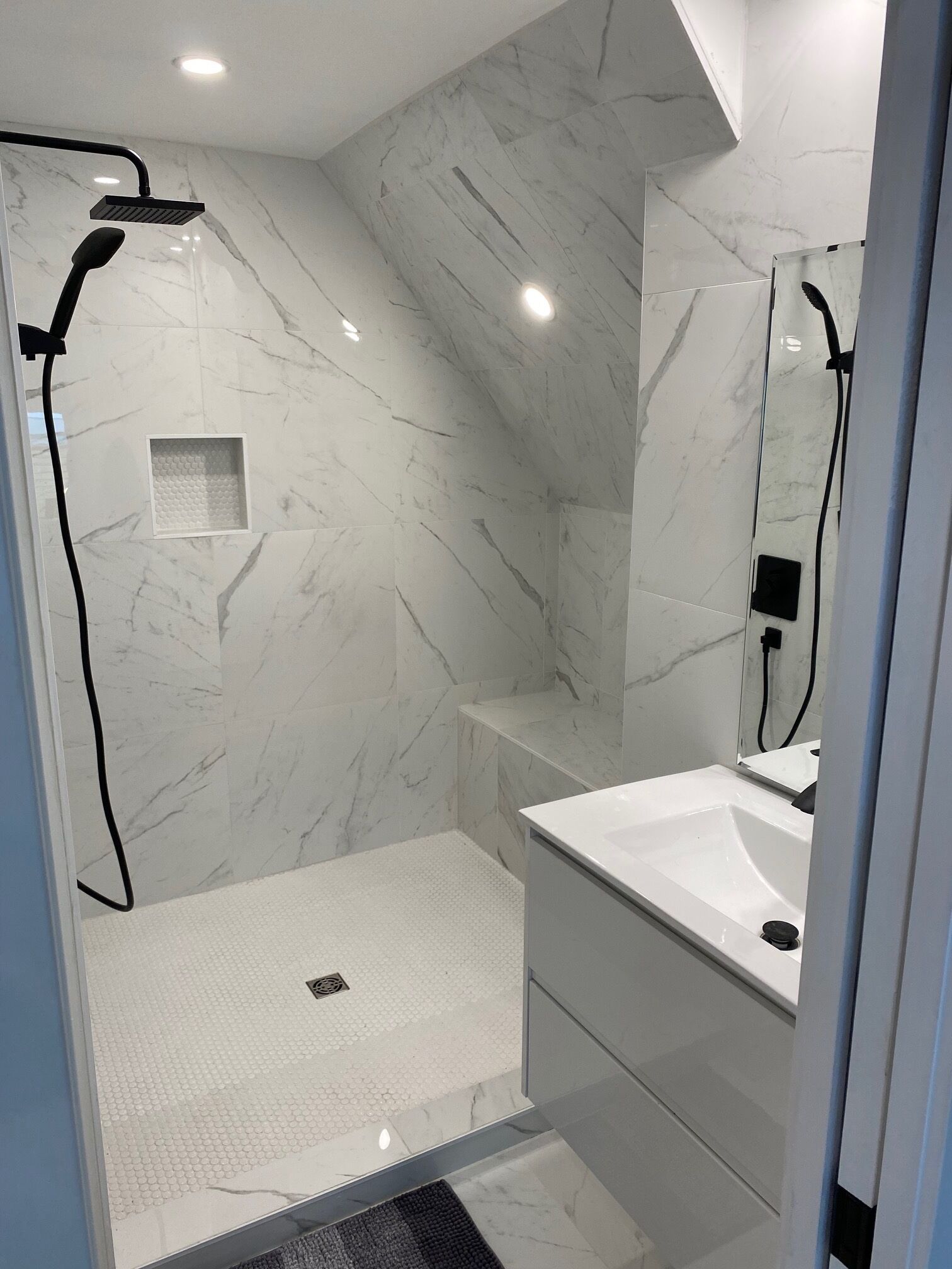 A modern bathroom with a shower, a sink, and a mirror.