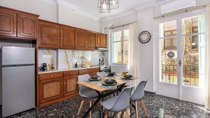 Une cuisine moderne avec des meubles en bois, un plan de travail en marbre et un coin repas avec une table dressée pour quatre personnes.