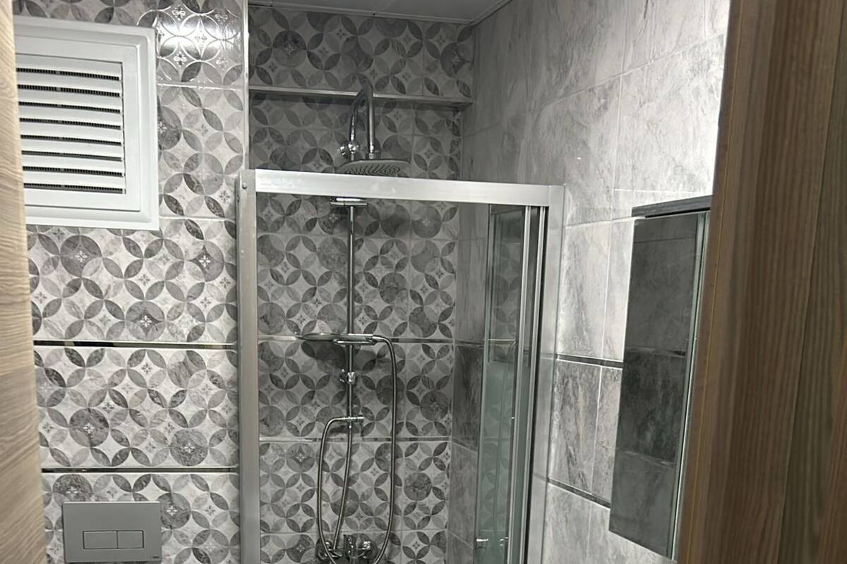 A compact bathroom with a shower, toilet, and washing machine.