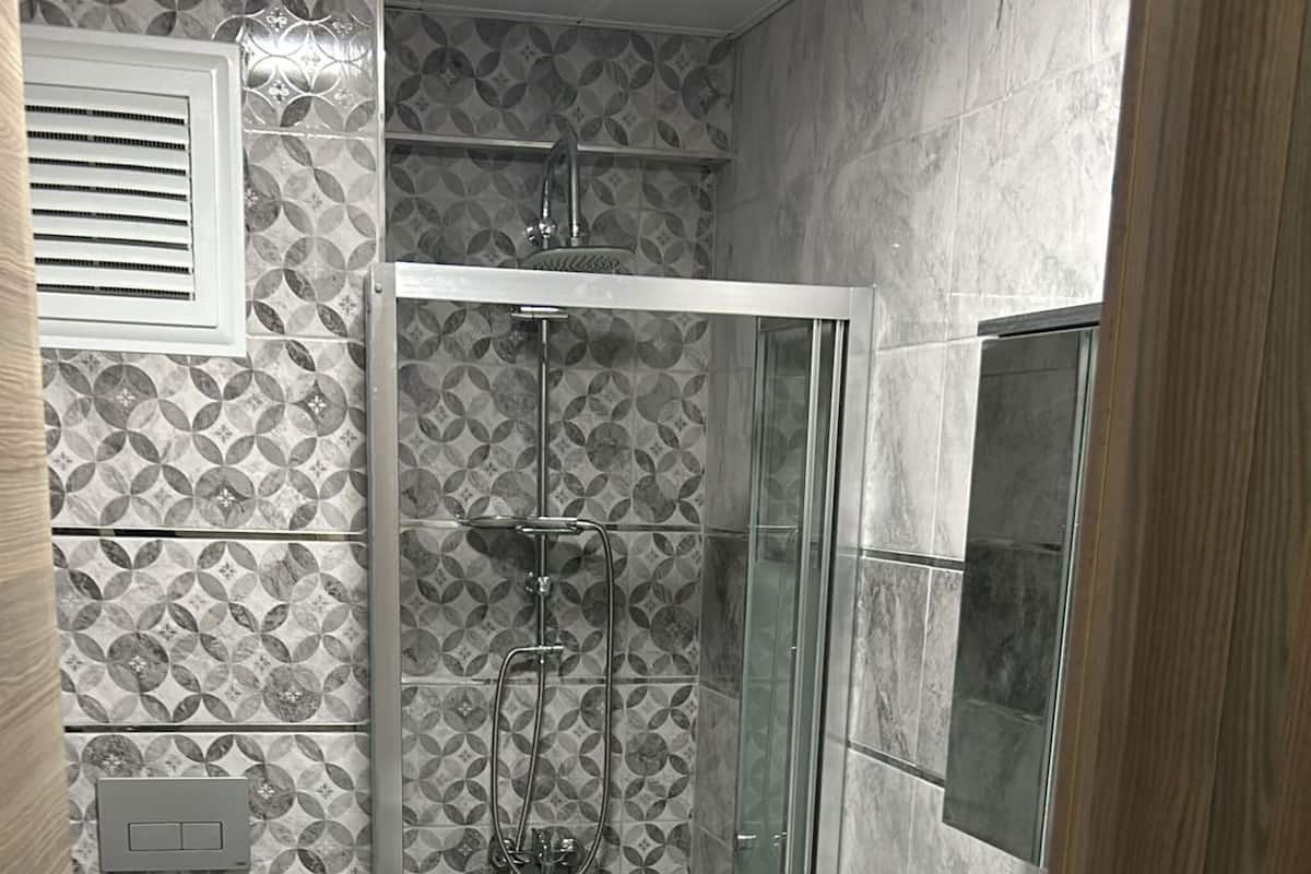 Une petite salle de bain comprenant une douche, des toilettes et un lave-linge.