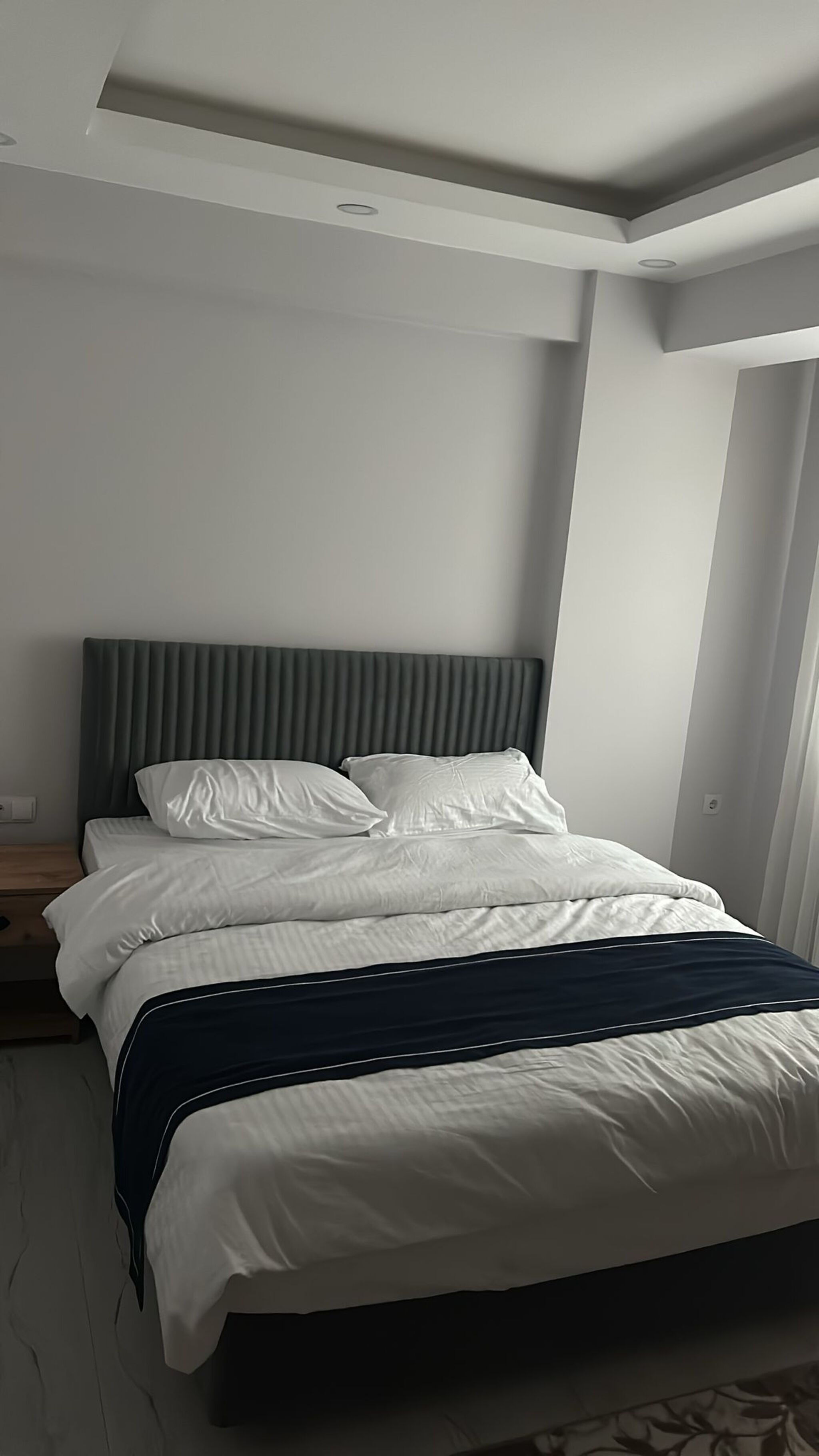 A modern bedroom with a bed, a headboard, and a nightstand.