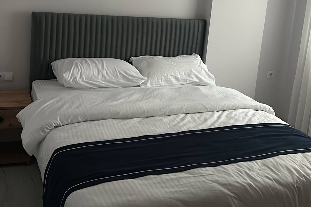 A modern bedroom with a bed, a headboard, and a nightstand.
