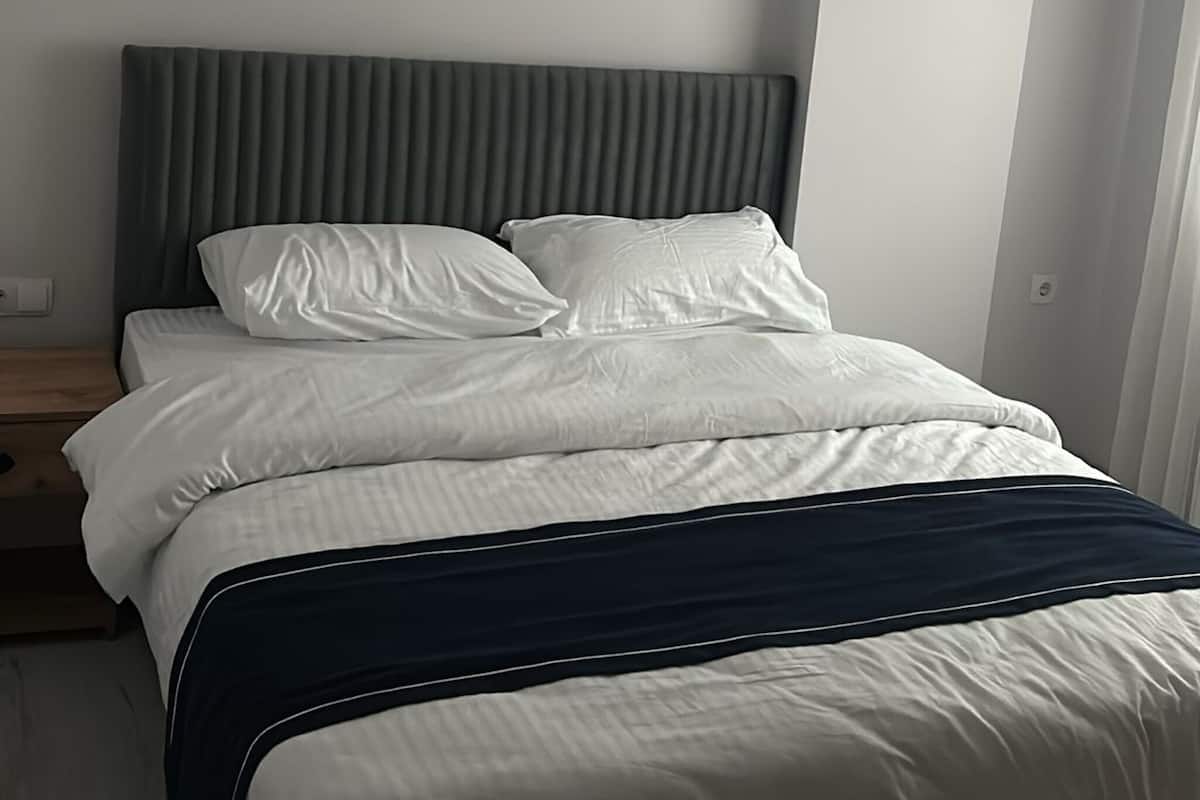 Une chambre à coucher moderne avec un lit, une tête de lit et une table de chevet.
