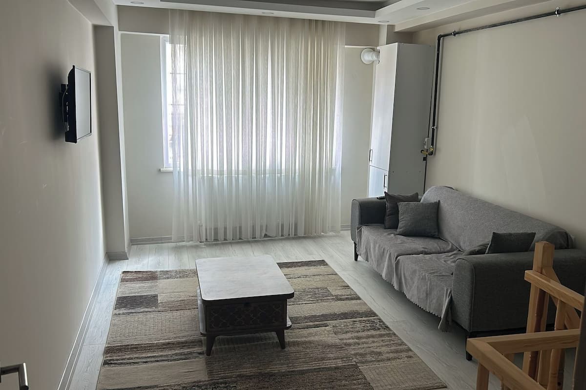 A living room with a sofa, a coffee table, and a TV mounted on the wall.