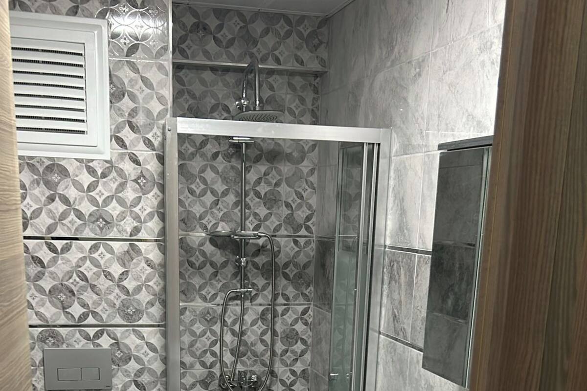 A compact bathroom with a toilet, a shower with a glass door, and a washing machine.