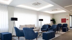 Eine moderne Lobby mit einem beigefarbenen Sofa, blauen Sessel und einem Couchtisch.