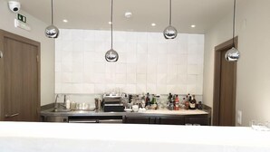 Eine moderne Küche mit einer zentralen Kochinsel, Edelstahlgeräten, hängenden Pendelleuchten und einer gefliesten Spritzschutzwand.