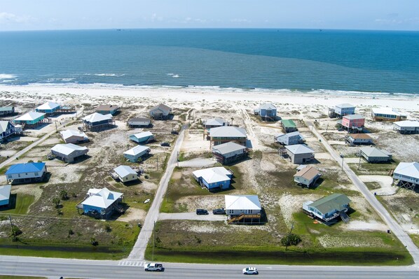 Vue aérienne d’une zone résidentielle côtière, avec des maisons et une plage.