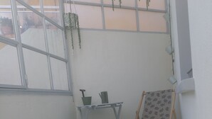 A small room with a window, a table with a green pot, a wooden chair, and a patterned rug. - Very quiet family home a stone's throw from the town center. (Perpignan)