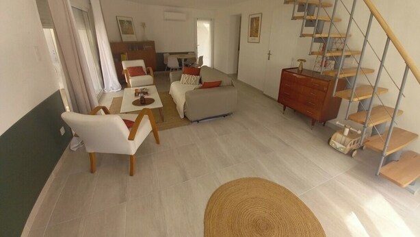 A spacious living area with a sofa, chairs, a dining table, a staircase, and a wooden cabinet. - Very quiet family home a stone's throw from the town center. (Perpignan)