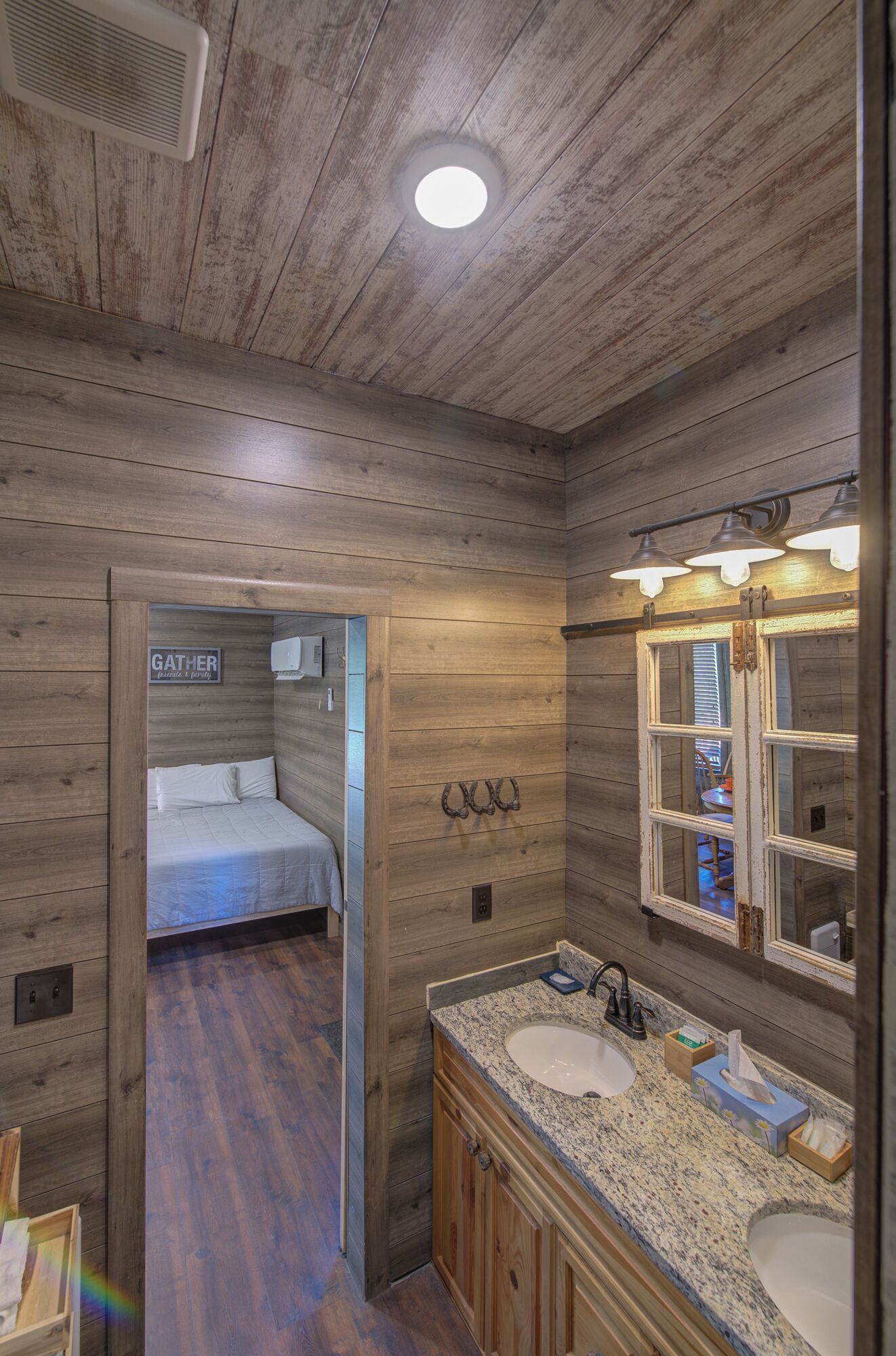 A wooden cabin-style bathroom with a large mirror, a sink, and a shower area.