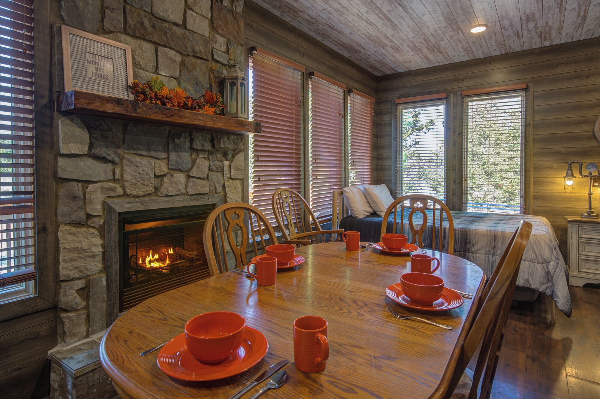 A cozy dining area with a stone fireplace, wooden dining table, and chairs.