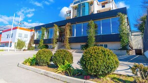 Um hotel moderno com fachada de vidro, entrada imponente e jardim frontal ajardinado.