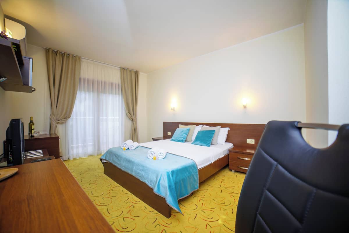 Una habitación de hotel con una cama, un escritorio, una silla y un televisor.
