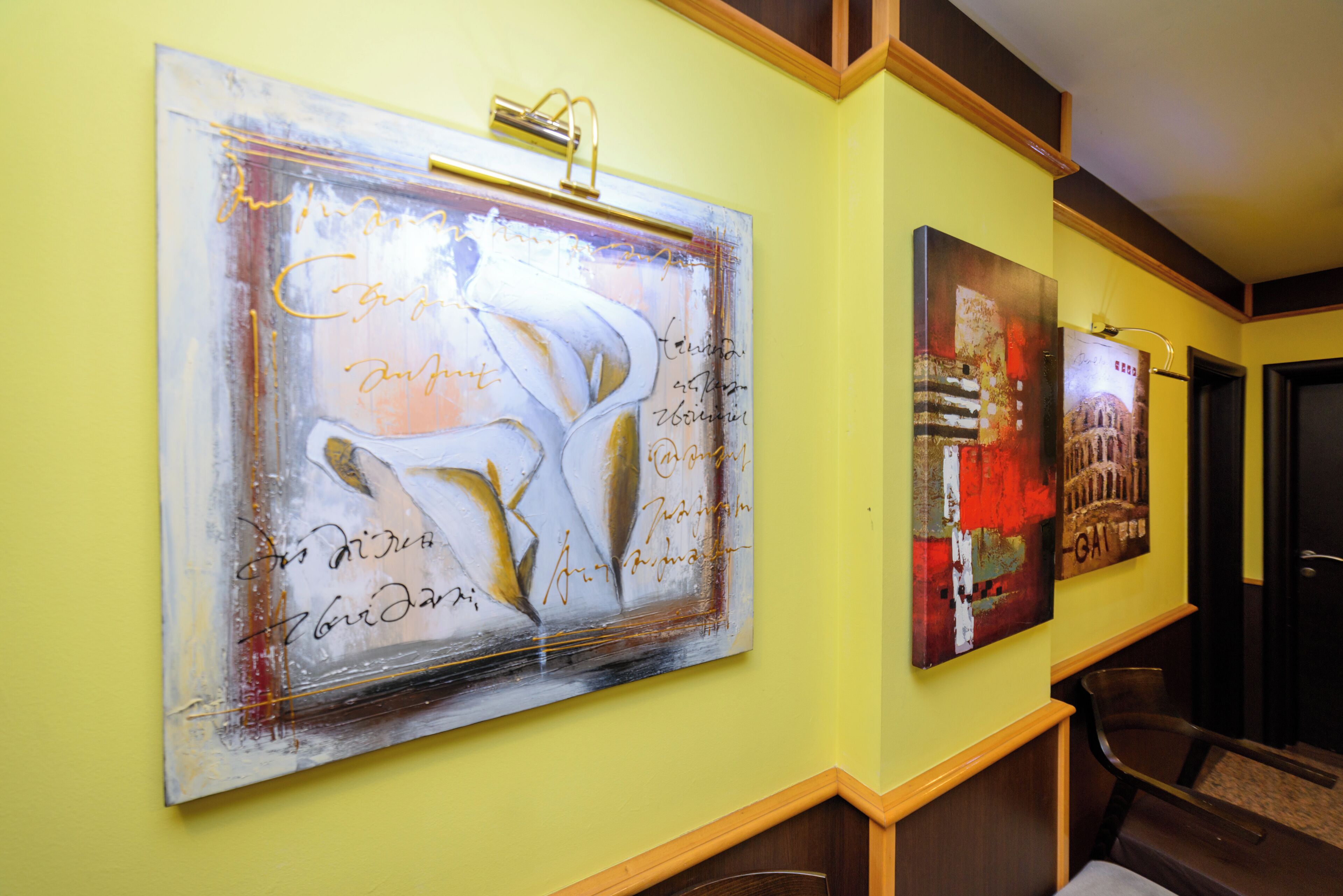 Um corredor com duas grandes pinturas abstratas na parede e um banco de madeira.