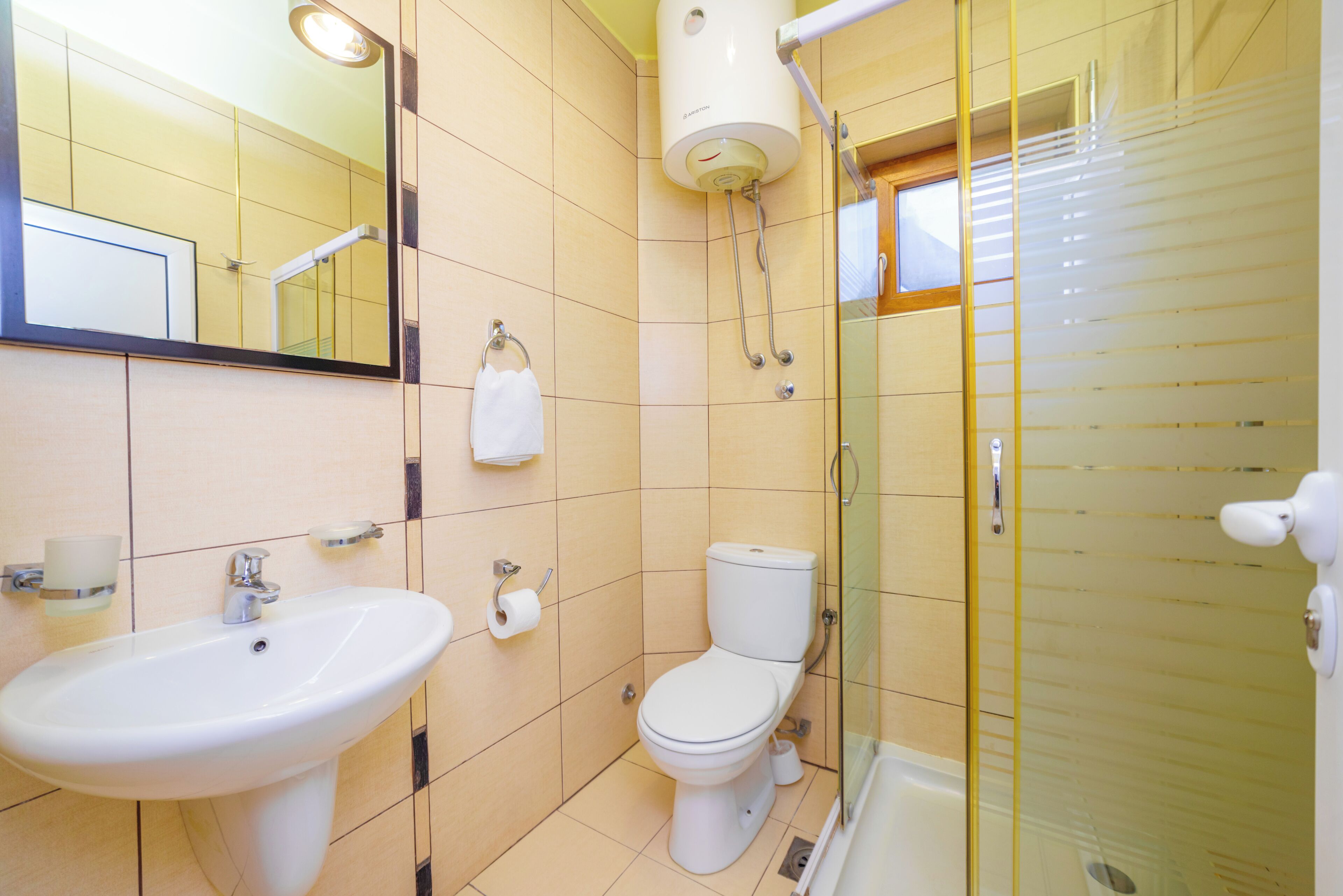 Un baño con lavamanos, inodoro y cabina de ducha de vidrio.