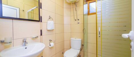Un baño con lavamanos, inodoro y cabina de ducha de vidrio.