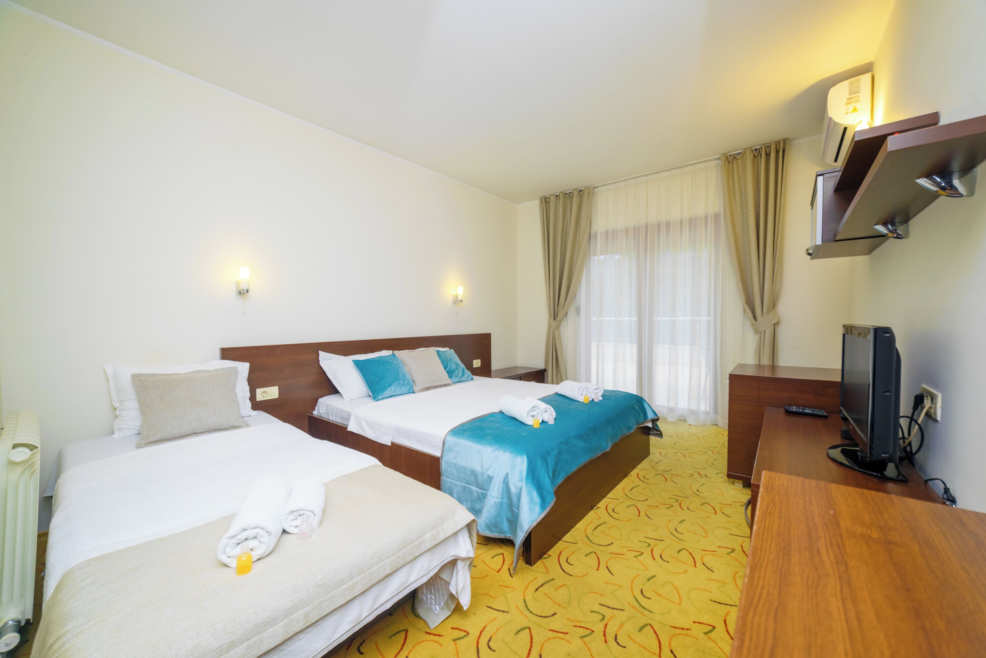 A hotel room with two beds, a TV, a desk, and a bathroom.