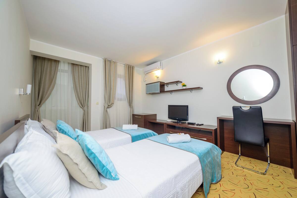 Una habitación de hotel con dos camas, televisión, escritorio y una silla.